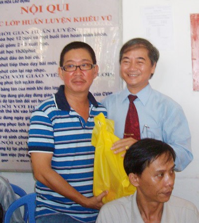 A representative from the Labor Union of HCMC (R) offers gift to disabled workers. (Photo:SGGP)